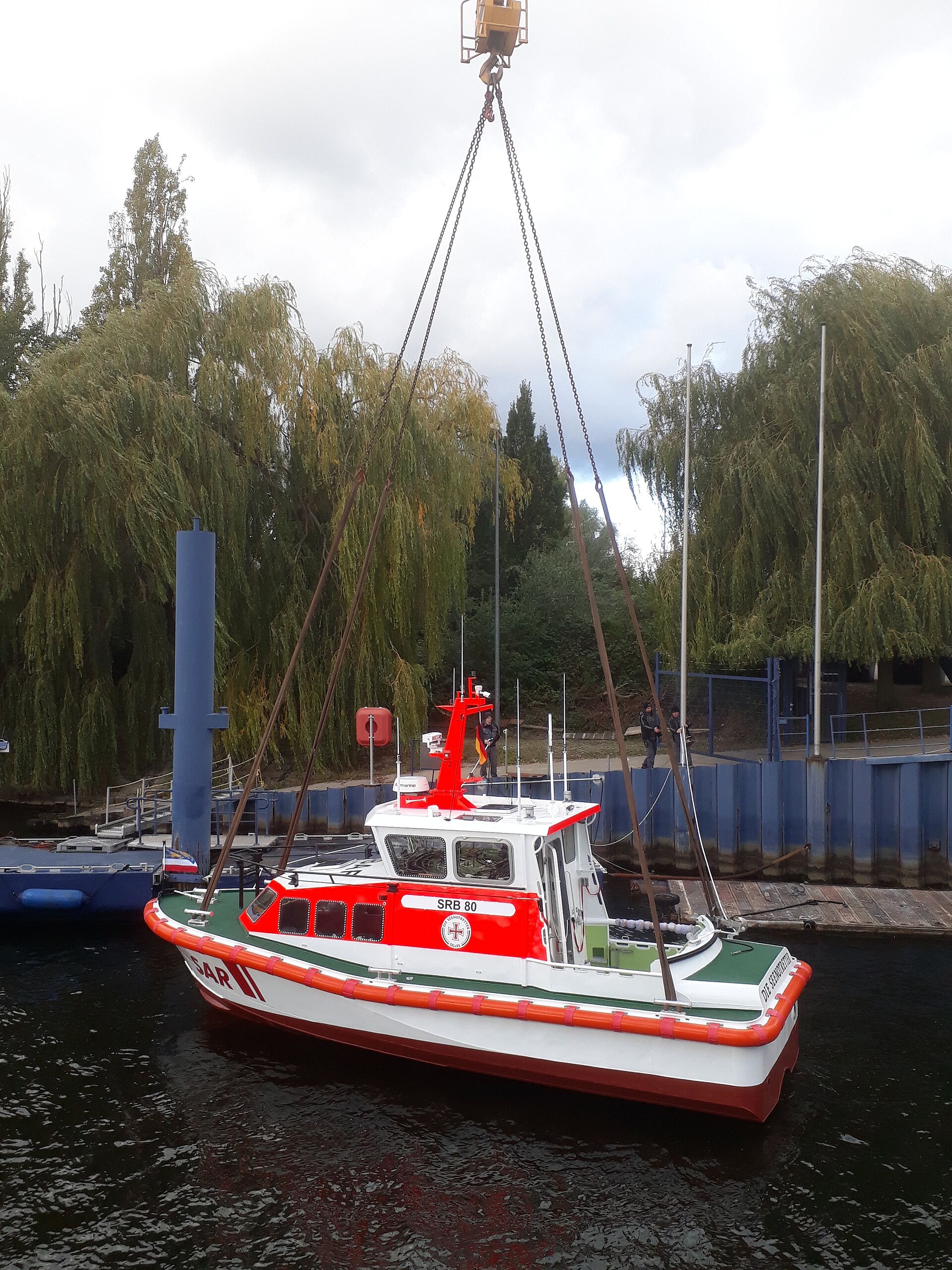 Das Seenotrettungsboot hängt am Kran über dem Hafenbecken der Werft.