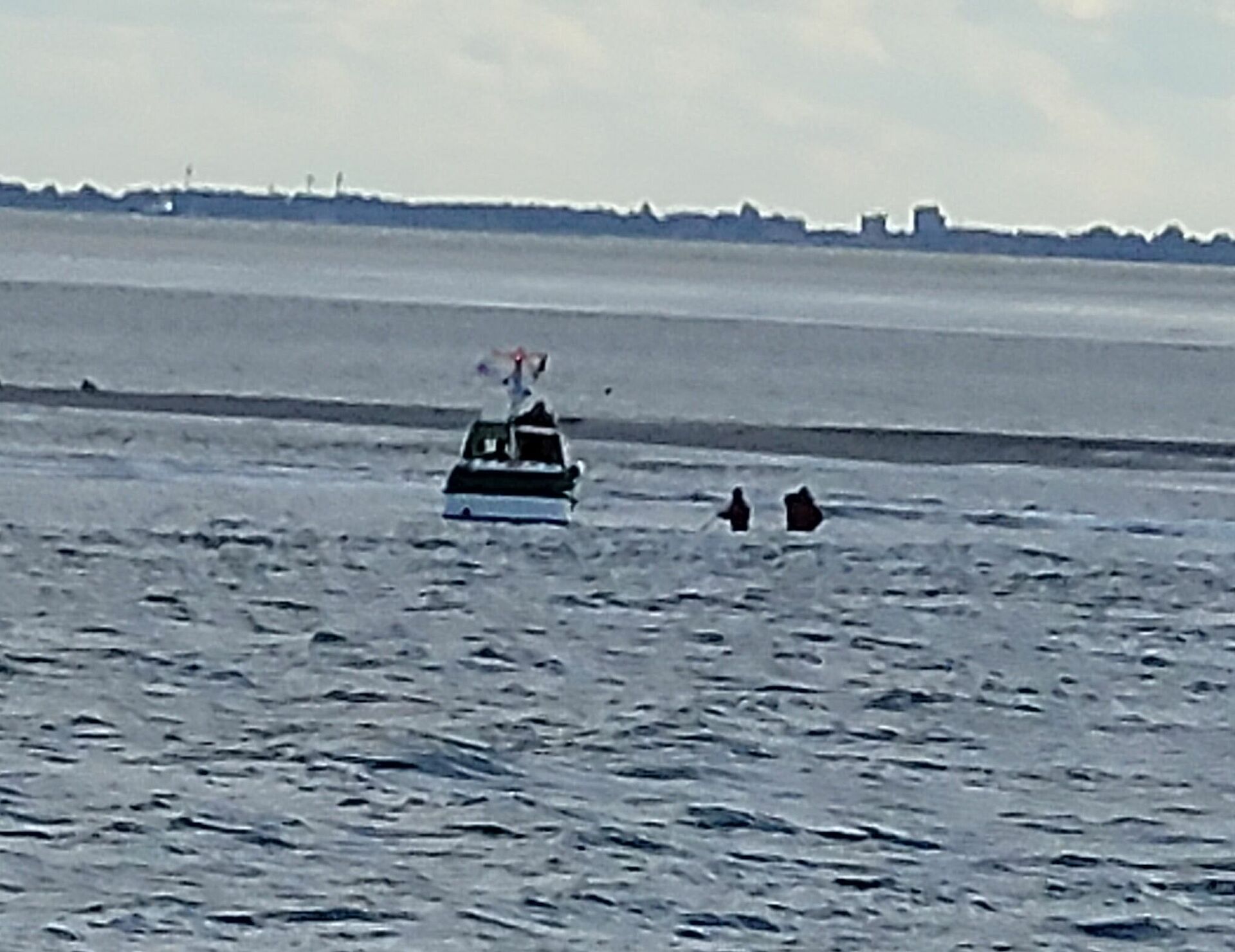 Menschen waten durch hohes Wasser durchs Watt zu einem Rettungsboot