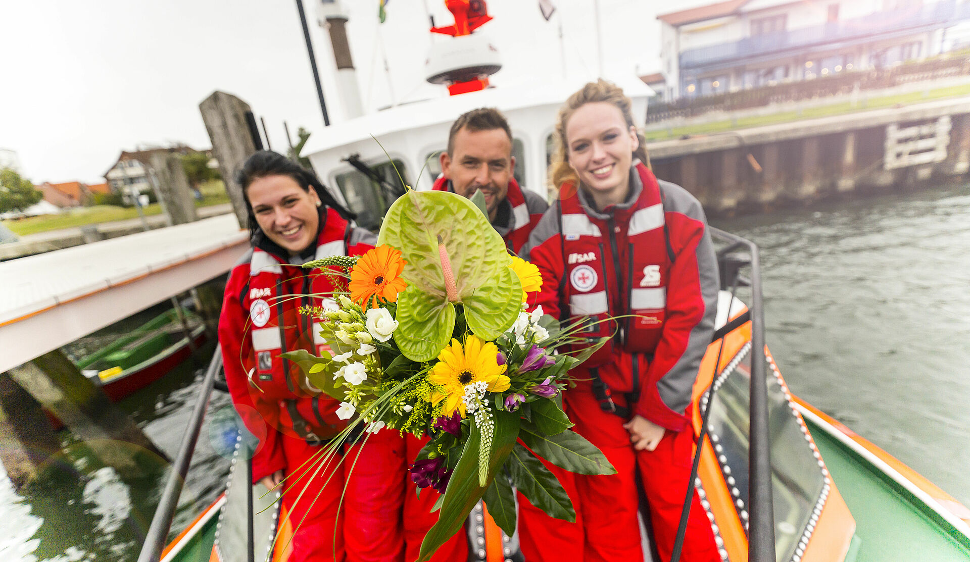3 Seenotretter halten einen Blumenstrauß in der Hand