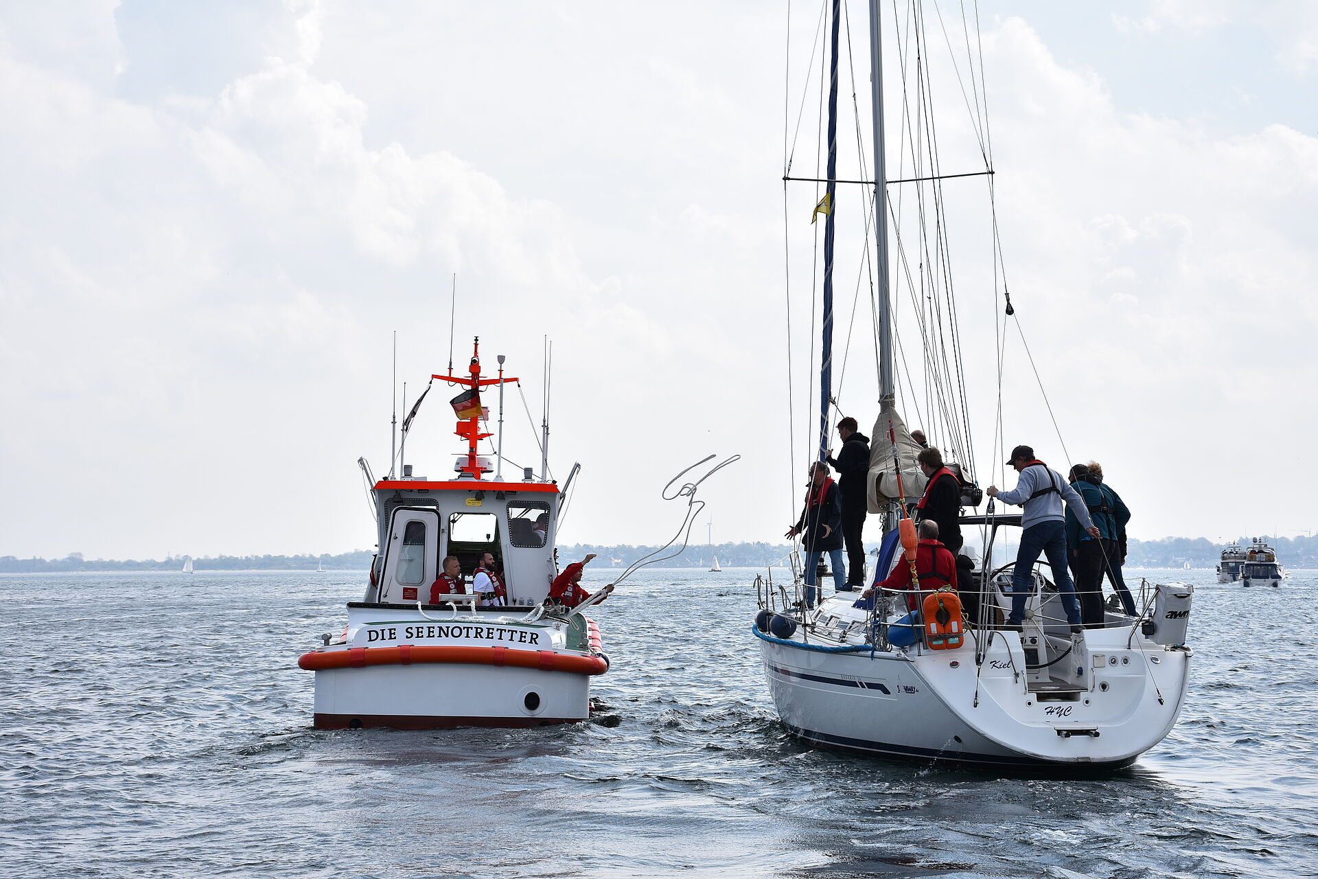 Die Seenotretter werfen von ihrem Seenotrettungsboot eine Leine zu einer nahegelegenen Segelyacht.