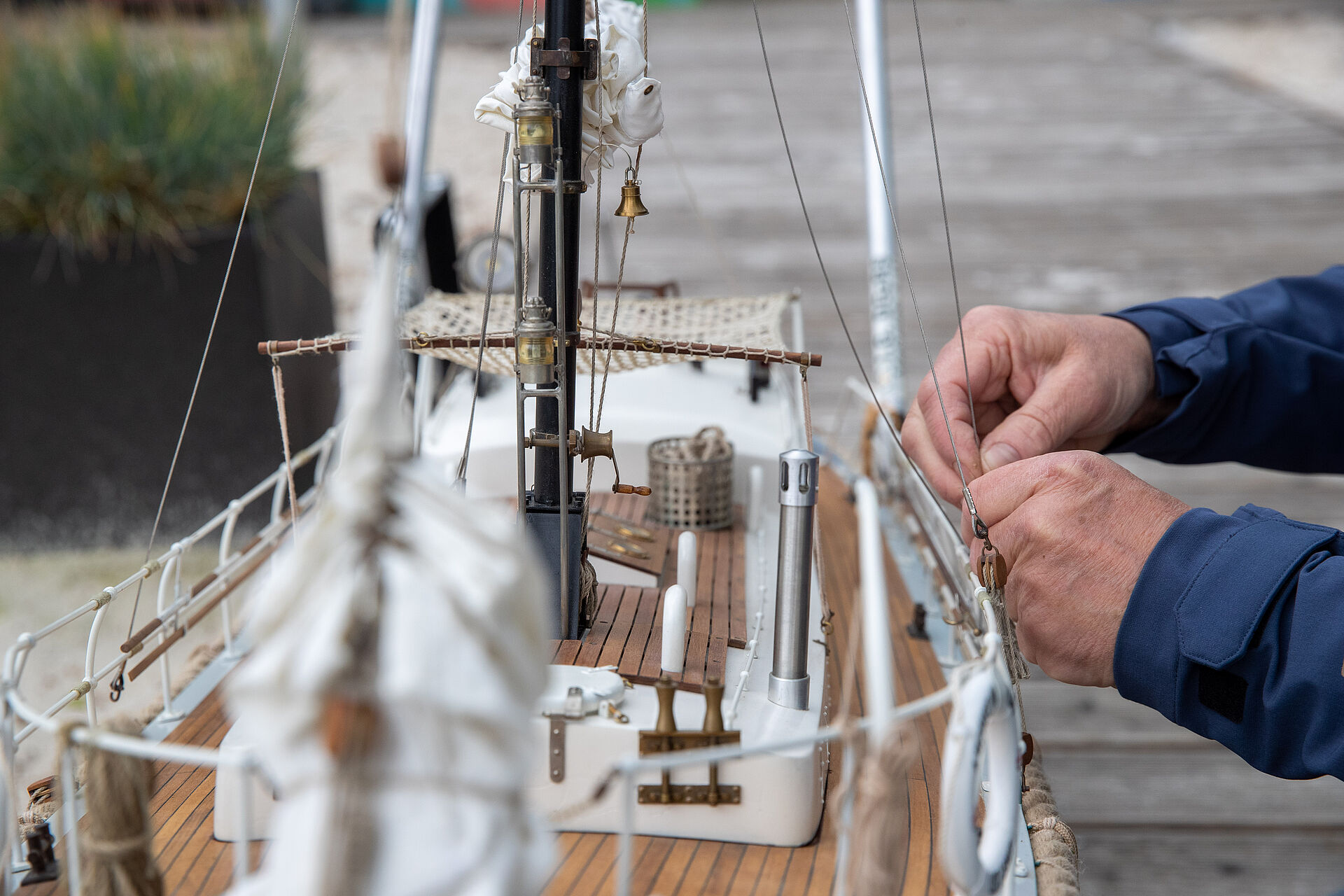 Ein Modellbauer bindet ein Metallseil an der Reling seines Modellbootes fest.