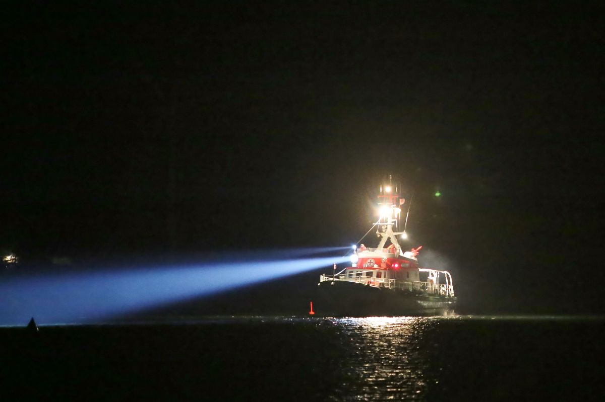 Seenotrettungskreuzer auf See mit eingeschaltetem Scheinwerfer in der Nacht