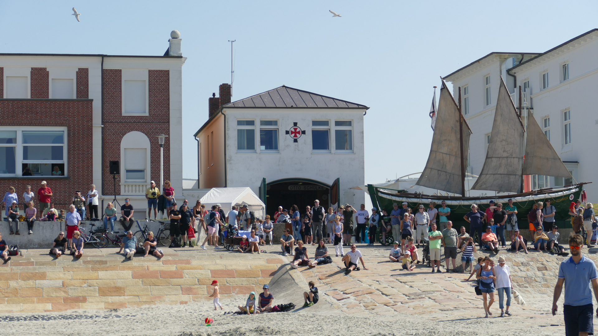 Menschen am Strand vor dem historischen Rettungsschuppen der Seenotretter