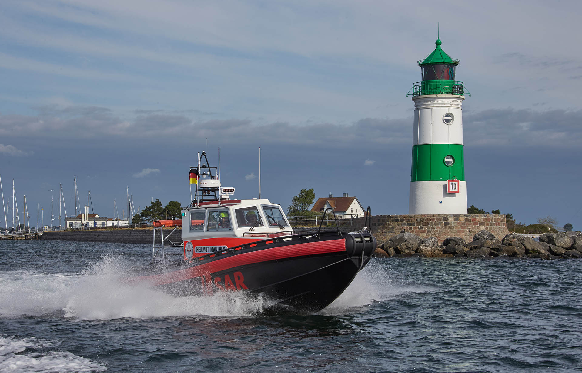 Das Seenotrettungsboot HELLMUT MANTHEY verlässt vorbei am grün-weißen Leuchtturm in Schleimünde die Schlei Richtung offene Ostsee.