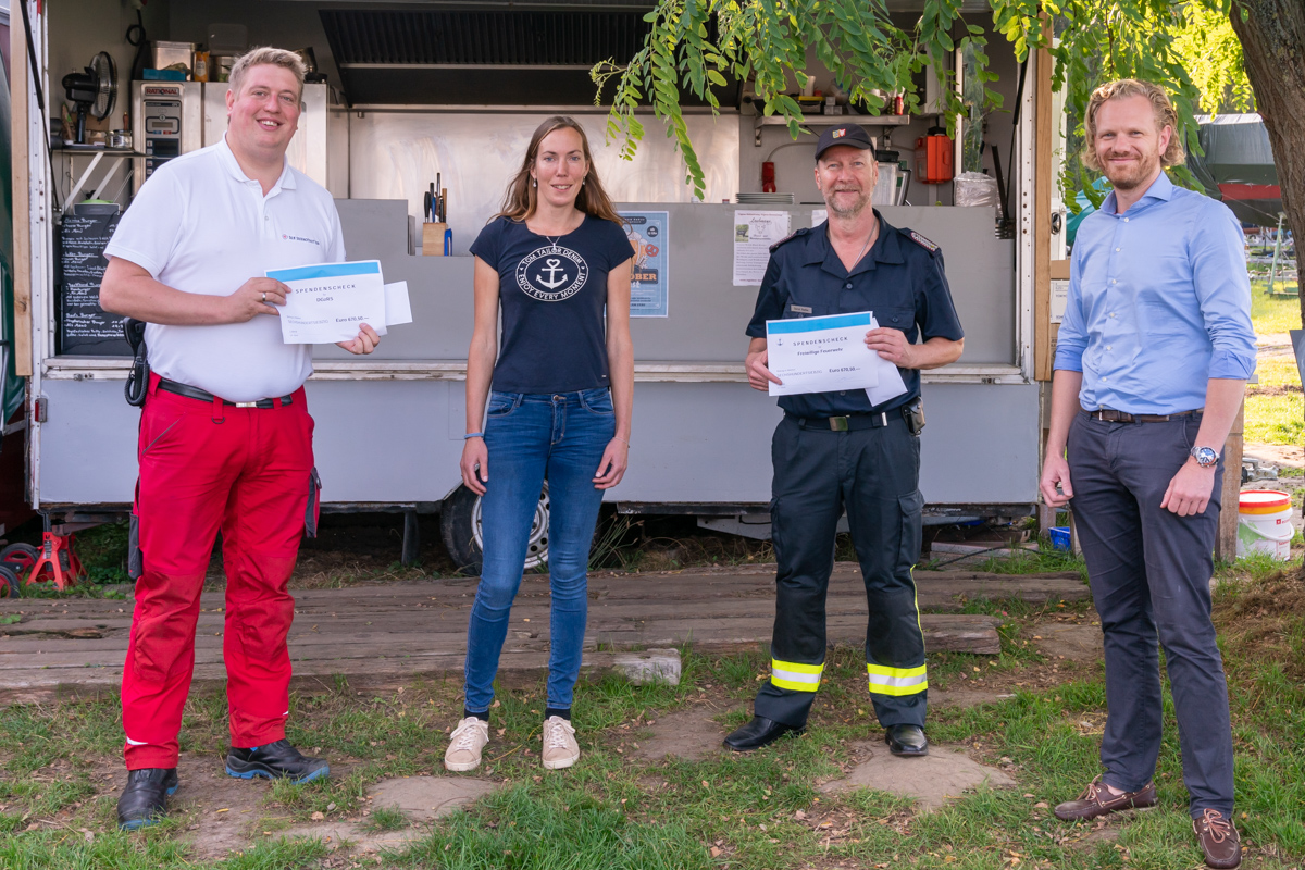 Seenotretter erhalten Checks vor einem Foodtruck