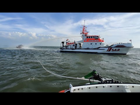 Ein Seenotretterkreuzer auf hoher See löscht eine Motoryacht